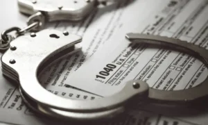 Handcuffs placed on top of a U.S. 1040 tax form, symbolizing tax fraud consequences.